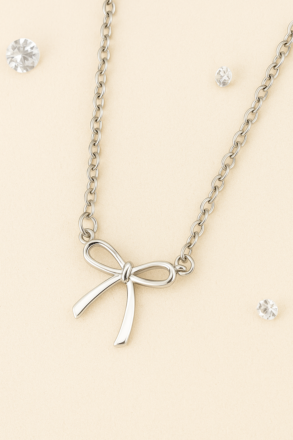 Silver bow necklace on a beige background