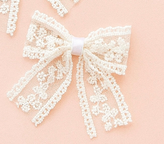 White lace bow on a pink background up close