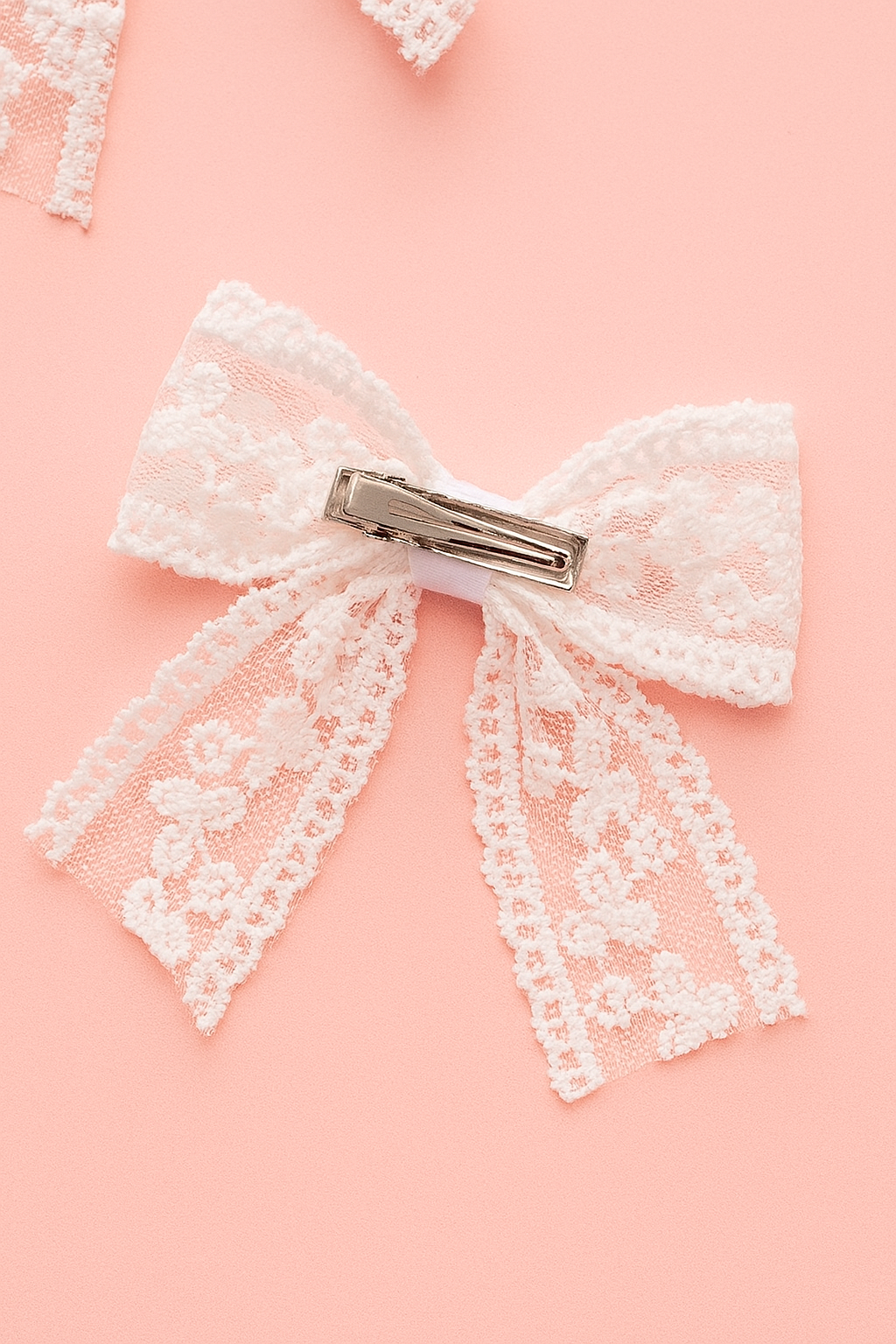 White lace bow with a clip on a pink background